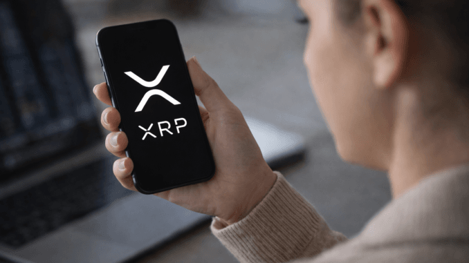 Person holding a smartphone displaying the XRP cryptocurrency logo while checking digital asset markets.